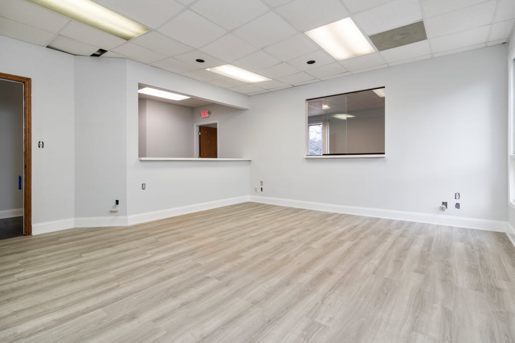 Modern and spacious empty room with wooden flooring and recessed lighting.